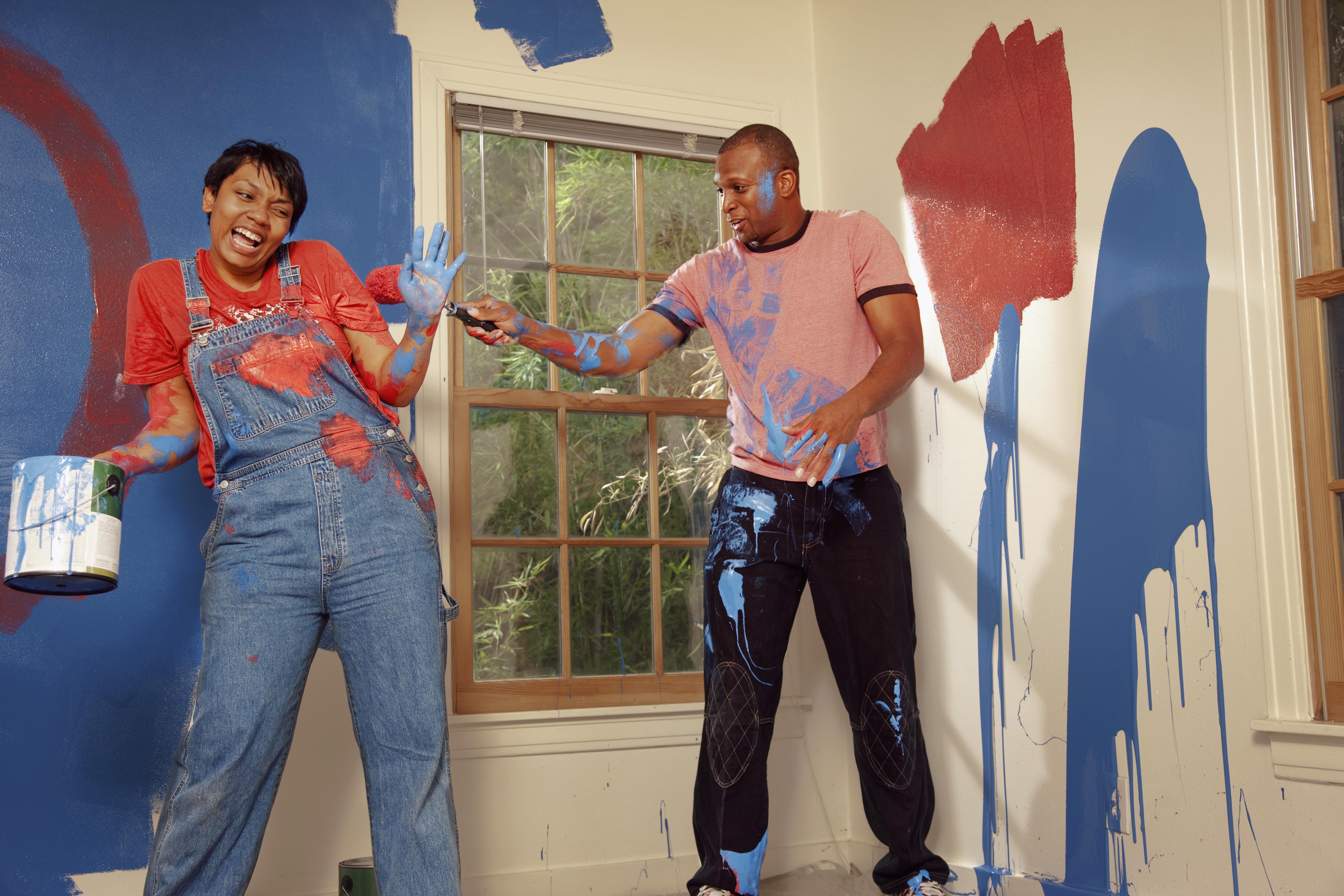 African American couple painting wall and making a mess