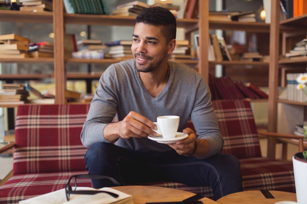 University student enjoying coffee break while studying in library.