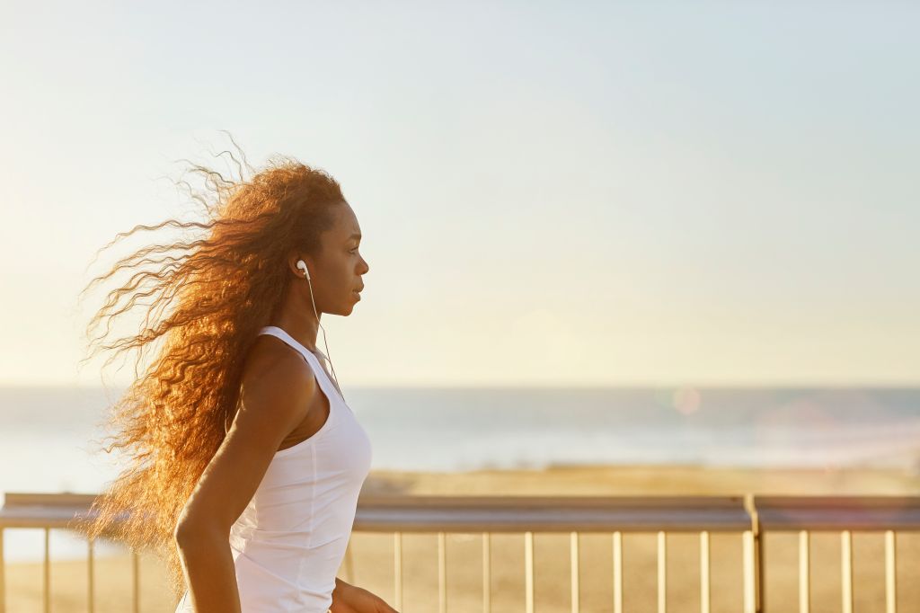 Sporty woman jogging at beach during sunny day