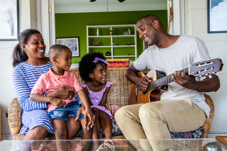 Father playing guitar to his family at home