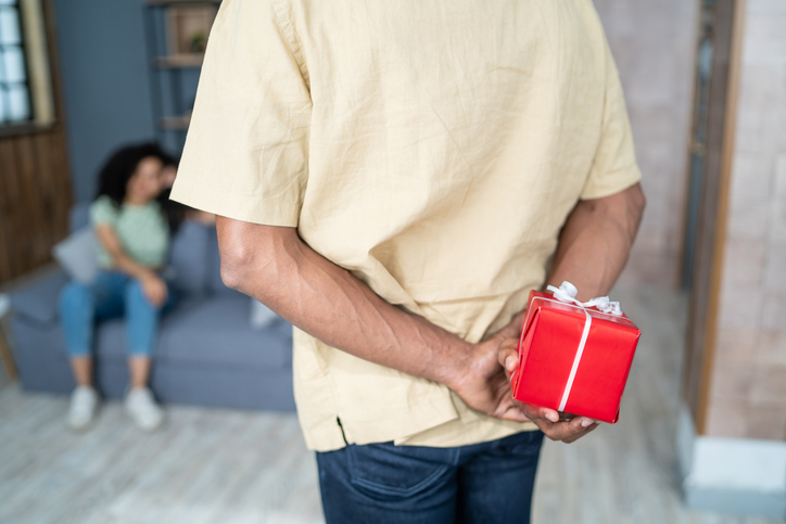 Man hiding a birthday present behind him